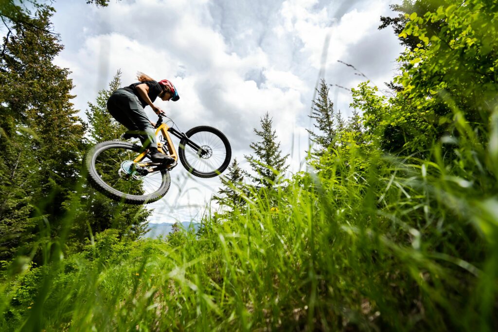 a rider in the air on a full suspension trek bike with grass in the foreground