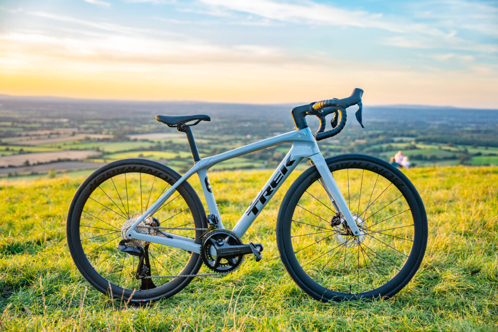 A grey Trek Domane SL 7 sits face on to camera on top of Devils Dyke looking out over the south downs